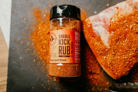 Creole Kick Rub spice container next to seasoned meat on a cutting board